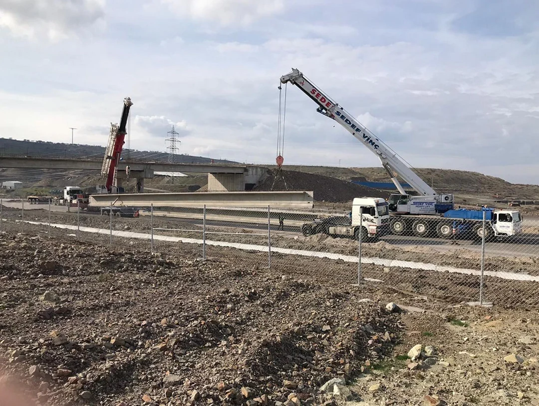 Uzun beton kirişin iki vinçle kaldırıldığı saha çalışması